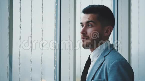 商人站在窗户附近男人环顾四周与世隔绝在白色模糊的背景上复制空间4K视频的预览图