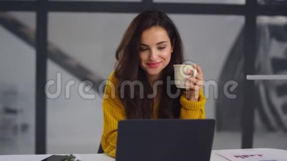 特写商务女性看笔记本电脑微笑的女孩在笔记本旁喝茶视频的预览图