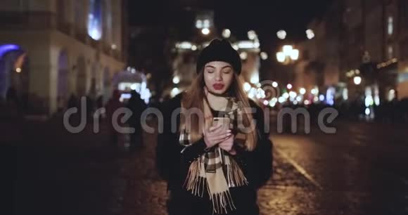 女人在城市的夜晚使用智能手机有吸引力的年轻女性发短信在手机户外交流女孩视频的预览图