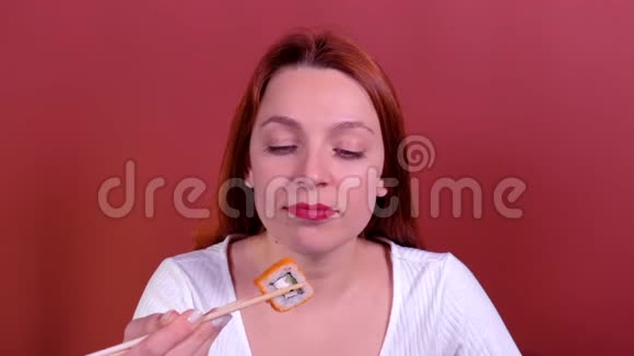 画红头发年轻女人用筷子吃寿司视频的预览图