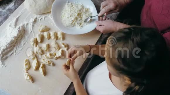 祖母带着孙女在家厨房里包着奶酪的饺子视频的预览图