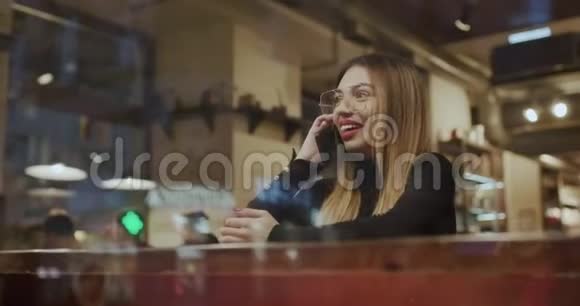 小女孩在咖啡馆里用智能手机使用手机的漂亮女人视频的预览图