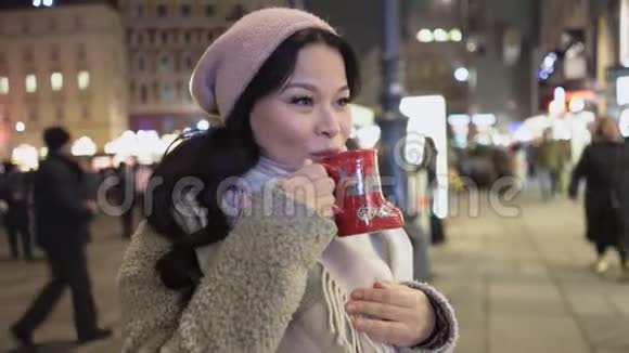 快乐的亚洲女人在户外基督弥撒之夜享受她的热咖啡视频的预览图