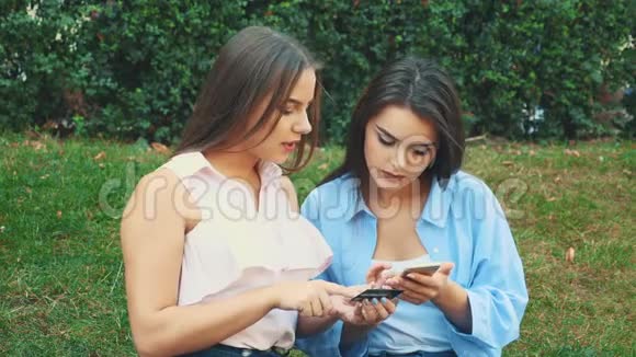 两个迷人的女孩正坐在公园的长凳上网上购物快关门复制空间4K视频的预览图