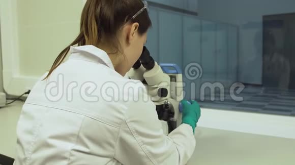 女性生物学家在显微镜下观察视频的预览图