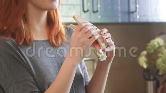 迷人的年轻红发女孩在周末在厨房里吃一个俱乐部三明治吃不饱的女人视频的预览图