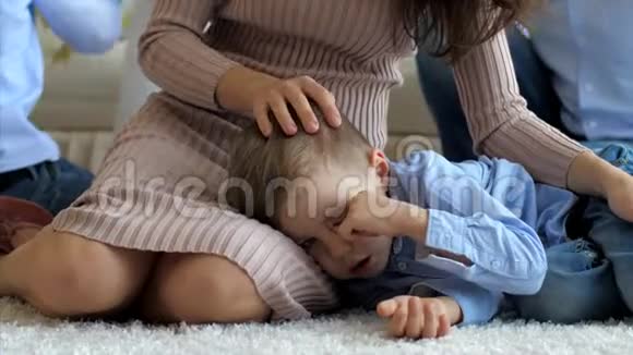 小儿子躺在妈妈膝盖上躺在地板上妈妈在抚摸他视频的预览图
