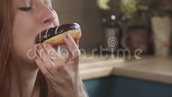 迷人的饥饿红发女孩吃甜甜圈在清晨周末在厨房不健康的饮食脂肪视频的预览图