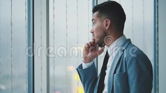 商人站在窗户附近人是隆电话他是孤立的在白色模糊的背景上复制空间4K视频的预览图
