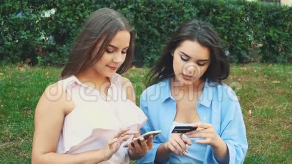 两个迷人的女孩正坐在公园的长凳上网上购物快关门复制空间4K视频的预览图