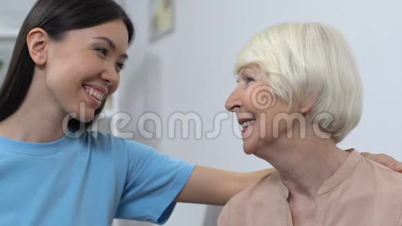 友善的年轻女士微笑着对待幸福的高级女士帮助老年人照顾家庭视频的预览图