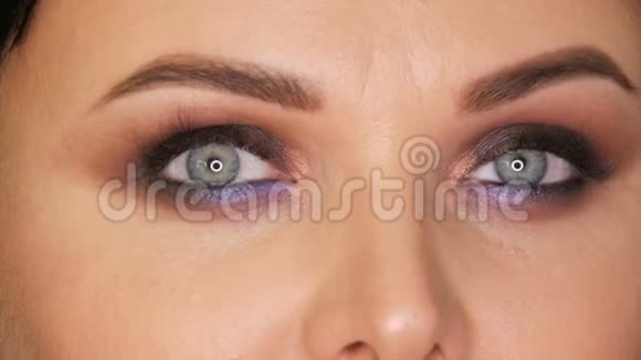 年轻美丽的女人明亮的蓝色眼睛和晚上化妆烟雾般的眼睛蓝色和紫色的眼影在黑色视频的预览图