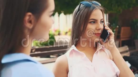 两个有魅力的年轻女人在一条夏天的街道上聊天快关门焦点是金发女孩她在打电话副本视频的预览图