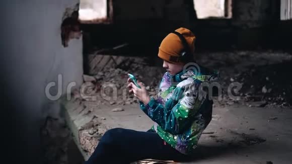 一个男孩坐在废弃的房子里听音乐视频的预览图