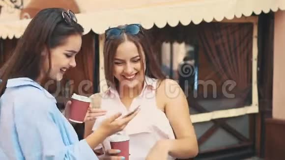 两个有魅力的年轻女人正在夏天的街道上聊天喝咖啡快关门复制空间4K视频的预览图