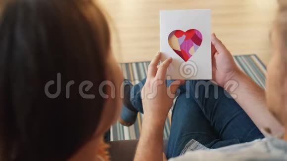 男人和女人拿着情人节卡片带着爱的忏悔拥抱在家里视频的预览图