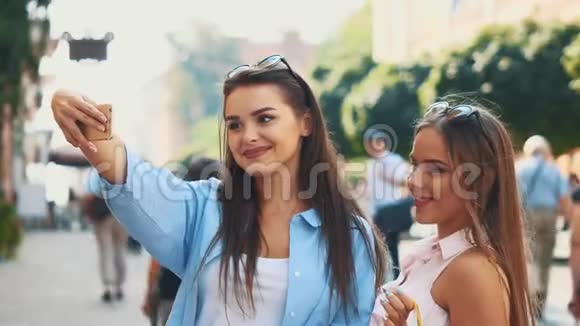微笑的十几岁女孩正在通过智能手机自拍正在夏季城市公园的背景复制空间快关门4K视频的预览图