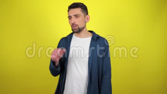 一个穿着蓝色衬衫和白色T恤的年轻人咳嗽着用拳头捂住嘴视频的预览图