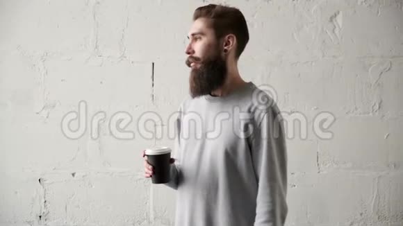 一个留着胡子的年轻人在窗外喝咖啡休息期间快乐的程序员视频的预览图