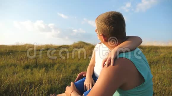 快乐的父亲和微笑的孩子在一起享受大自然的乐趣快乐的爸爸坐在草地上视频的预览图
