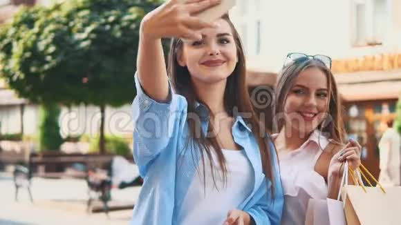 微笑的十几岁女孩正在通过智能手机自拍正在夏季城市公园的背景复制空间快关门4K视频的预览图