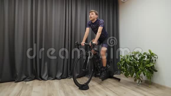 将男性自行车安装在自行车教练的家里运动员在室内骑自行车进行艰苦训练虚拟自行车概念年轻有信心视频的预览图