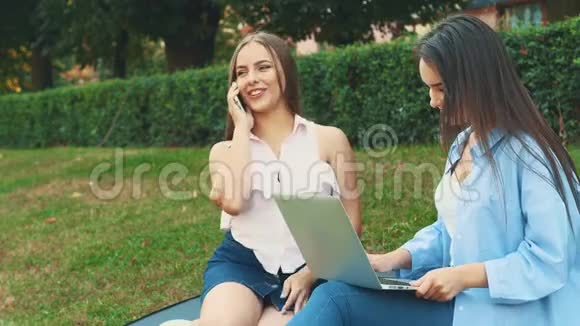 迷人的黑发女孩学生正在使用笔记本电脑在市中心受到自然美的启发她的朋友金发视频的预览图