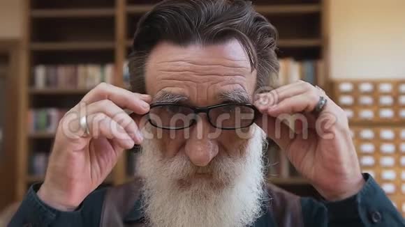有经验的长胡子的帅哥满脸皱纹戴上眼镜对着镜头真诚地微笑视频的预览图