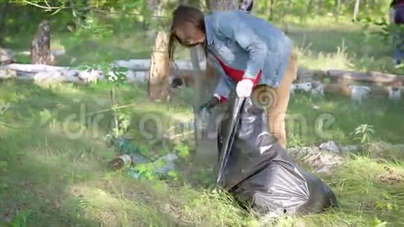 一群志愿者正在夏天打扫森林成年妇女正在树旁收集塑料瓶视频的预览图