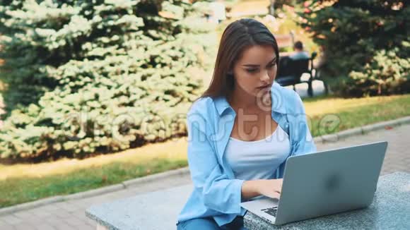 迷人的黑发女孩学生正在使用笔记本电脑在市中心受到自然美的启发快关门复制空间视频的预览图