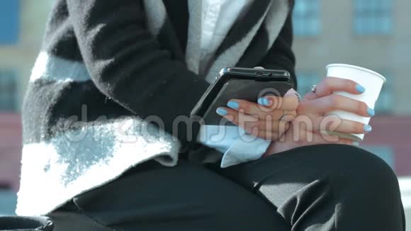 商务女性手里拿着一杯咖啡和一部手机视频的预览图