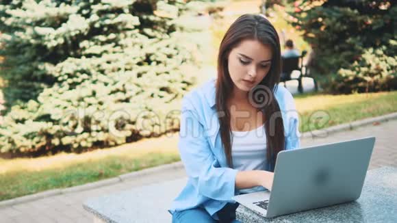 迷人的黑发女孩学生正在使用笔记本电脑在市中心受到自然美的启发快关门复制空间视频的预览图