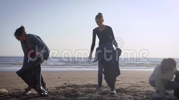 一群年轻女性在夏天早上从塑料垃圾中清理海滩打扫领地休息视频的预览图