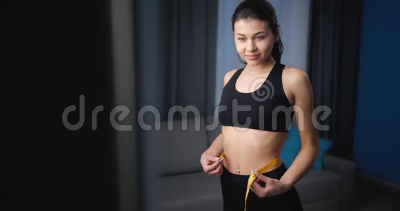 满意的女人用胶带测量她的腰部视频的预览图