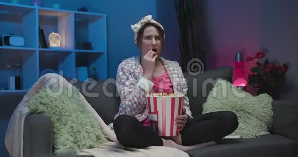 心烦意乱的女人哭着在电视上看悲伤的电影独自坐在沙发上不快乐的年轻人消极的情绪和视频的预览图