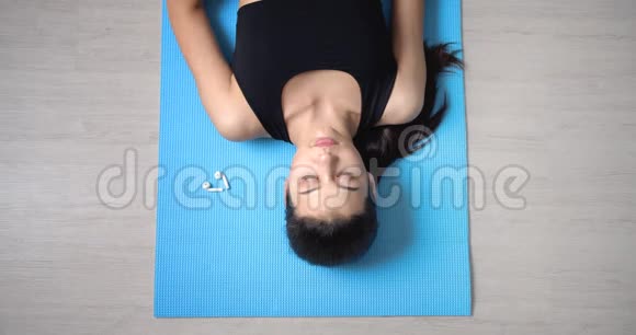 女人躺在地板上听耳机里的音乐视频的预览图