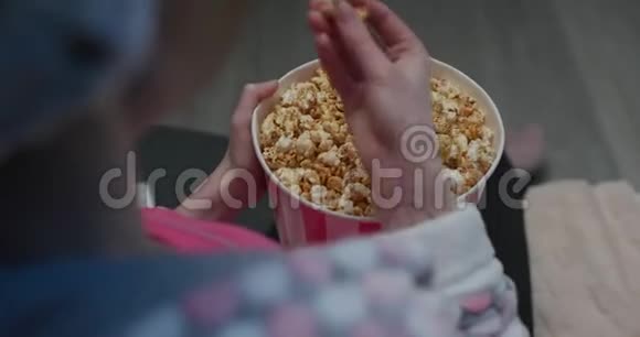 手挖进装满爆米花的桶里寻找完美的一块在电影院里手拿爆米花视频的预览图