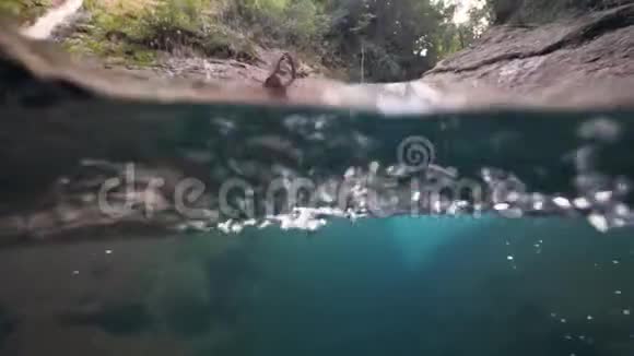 夏天一位勇敢的女游客跳进瀑布里的湍急的小溪里视频的预览图