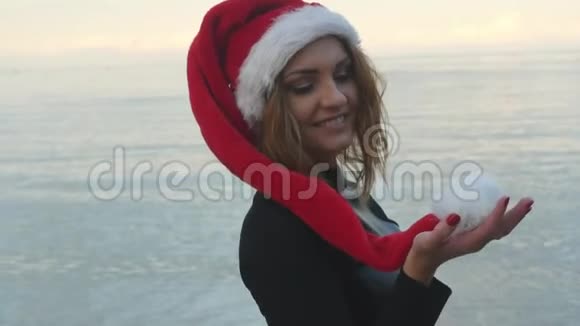 戴着圣诞帽的漂亮女人站在海边视频的预览图