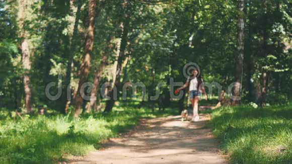 狗狗旁边的一个女孩高兴地跑过小路在自然公园复制空间4K视频的预览图