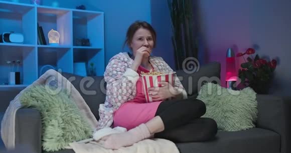 悲伤的女人坐在沙发上看情节剧悲伤的电影晚上在客厅里哭视频的预览图