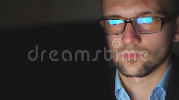 戴眼镜的经理的男性面孔在深夜笔记本电脑上工作的屏幕灯反射年轻的商人视频的预览图