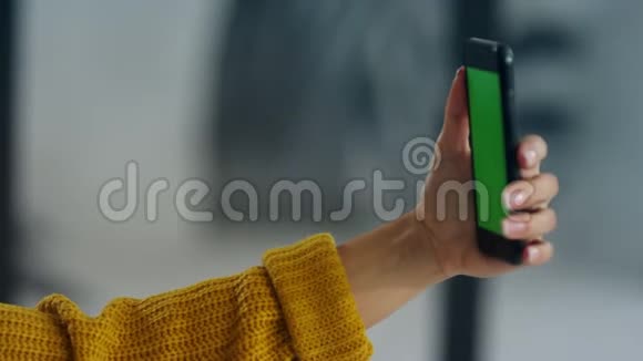 女人手拿着手机和绿色屏幕扮自拍的女孩视频的预览图