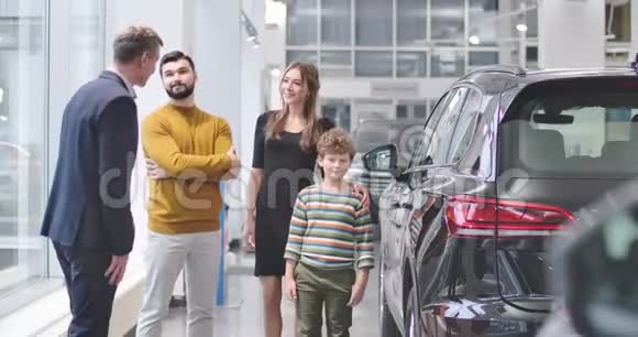 四个白人站在汽车经销商的新汽车旁边商人摇着成年胡须男手快乐视频的预览图