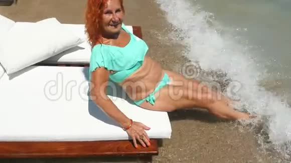 年轻的老妇人穿着蓝色比基尼在海边玩得很开心视频的预览图