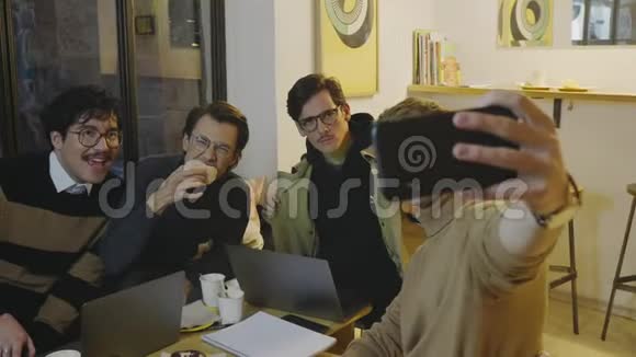商人在咖啡馆的智能手机上谈论自拍使用智能手机的朋友视频的预览图