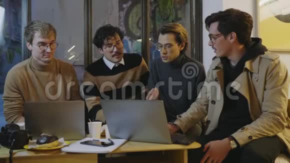 在咖啡馆里讨论的商人看手提电脑屏幕的同事视频的预览图