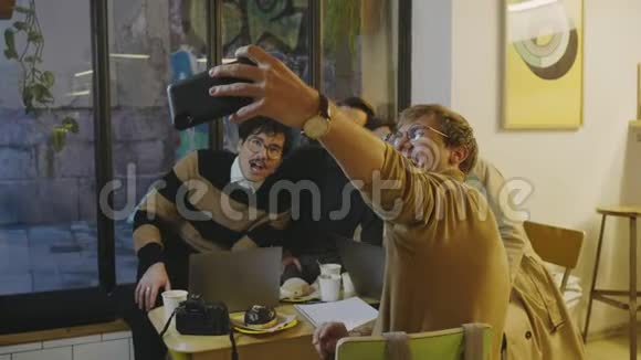 商人在智能手机上自拍在手机摄像头上做鬼脸的朋友视频的预览图
