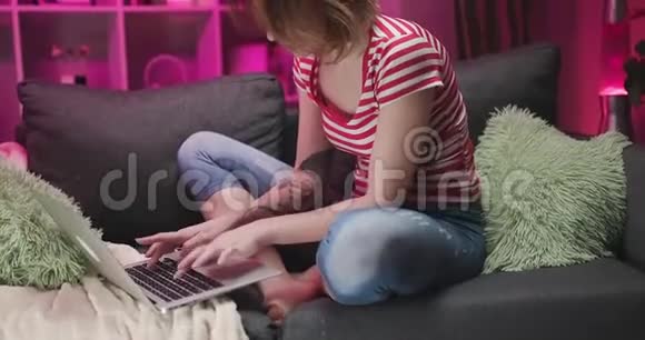 女人在沙发上用笔记本电脑年轻女子在客厅里用笔记本电脑与家人朋友聊天视频的预览图