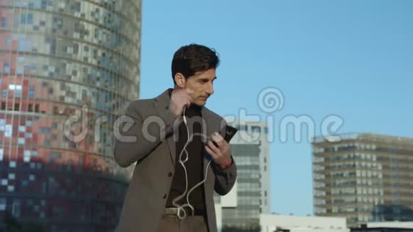 商人在街上拿着耳机走路员工在外面使用耳塞视频的预览图